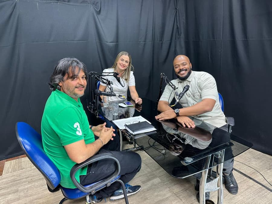 Cézar Ribeiro em entrevista de podcast, ao lado dos dois apresentadores